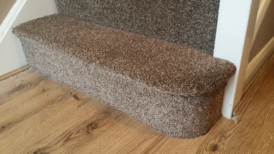 a carpeted stair and woodgrain vinyl floor